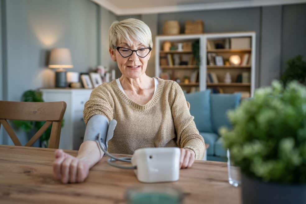 One woman senior caucasian female use blood pressure device on hand to check health results while sit at home real people health care concept